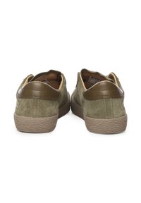 Zapatos de ante verde oliva con detalles en cuero marrón, suelas de goma texturizadas y detalles de costura, con un diseño de bajo respaldo.