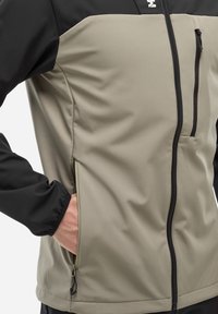 Veste pour homme avec une partie supérieure noire et une partie inférieure gris clair. Poches zippées, tissu lisse et ourlet ajustable.