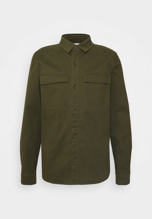 Camicia verde oliva a maniche lunghe con bottoni, due tasche anteriori sul petto e colletto classico, mostrata su sfondo bianco.