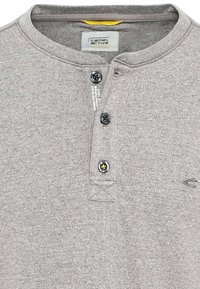 Grå tekstureret polo shirt med henleykrave, tre sorte knapper og et logo broderet i en kontrastfarve foran.