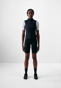 Svart sykkelvest med halv glidelås, kombinert med svarte shorts. Ensemblet har en slim fit, lett stoff, og kontrasterende lysegrå ermer.