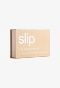 Beige box pakkaus, jossa on etiketti "slip" ja joka sisältää puhtaan silkkipussin. Pertuu teksti etuuksista: ikääntymistä ehkäisevä, unen uurteita ehkäisevä, sängyn päätä ehkäisevä.