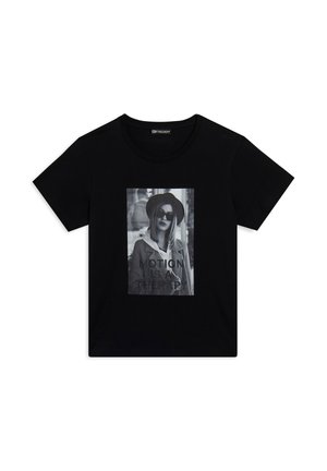T-shirt en coton noir avec un imprimé graphique sur le devant représentant une femme portant des lunettes de soleil, avec le texte "LE MOUVEMENT EST UNE THÉRAPIE" en gras. Manches courtes.