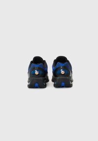 Schwarze und blaue Sportschuhe mit einem strukturierten Mesh-Obermaterial, gepolstertem Kragen und einer gemusterten Sohle mit blauen Akzenten. Sichtbares Luftpolster-Detail.