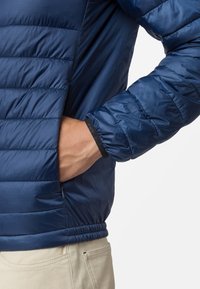 Marinfärgad isolerad jacka med kviltad design, elastiska ärmslut och en sidoficka. Tillverkad av glatt, lätt material.