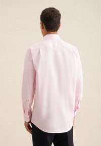Camicia a maniche lunghe di un delicato rosa chiaro, con colletto classico e polsini abbottonati, caratterizzata da una texture liscia e un orlo dritto.