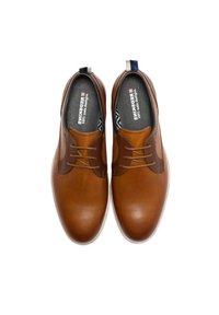 Chaussures en cuir marron avec une texture lisse, présentant un accent beige et des lacets marron. À l'intérieur, elles possèdent une doublure noire avec un motif géométrique.