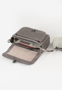 Borsa in pelle grigia con pattina superiore, interno a righe e numerosi scomparti, inclusa una sezione con zip e una superficie liscia.