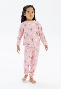 Juego de pijama infantil rosa que incluye una camiseta de manga larga y pantalones a juego, decorados con patrones de animales coloridos y arcoíris. Textura suave.