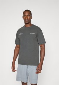 Gray cotton t-shirt with white Nike and Chevrolet logos on the chest, paired with light blue shorts featuring a textured pattern.