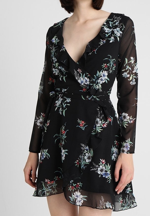 Schwarzes fliederblores Wickelkleid mit langen, transparenten Ärmeln, rüschenbesetztem Ausschnitt und einer Schleife in der Taille. Es zeichnet sich durch ein florales Muster in Blau, Weiß und Rot aus.