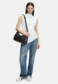 Top bianco senza maniche, jeans azzurri chiari strappati e borsa a spalla nera in pelle con due tasche frontali, abbinata a sneakers bianche.