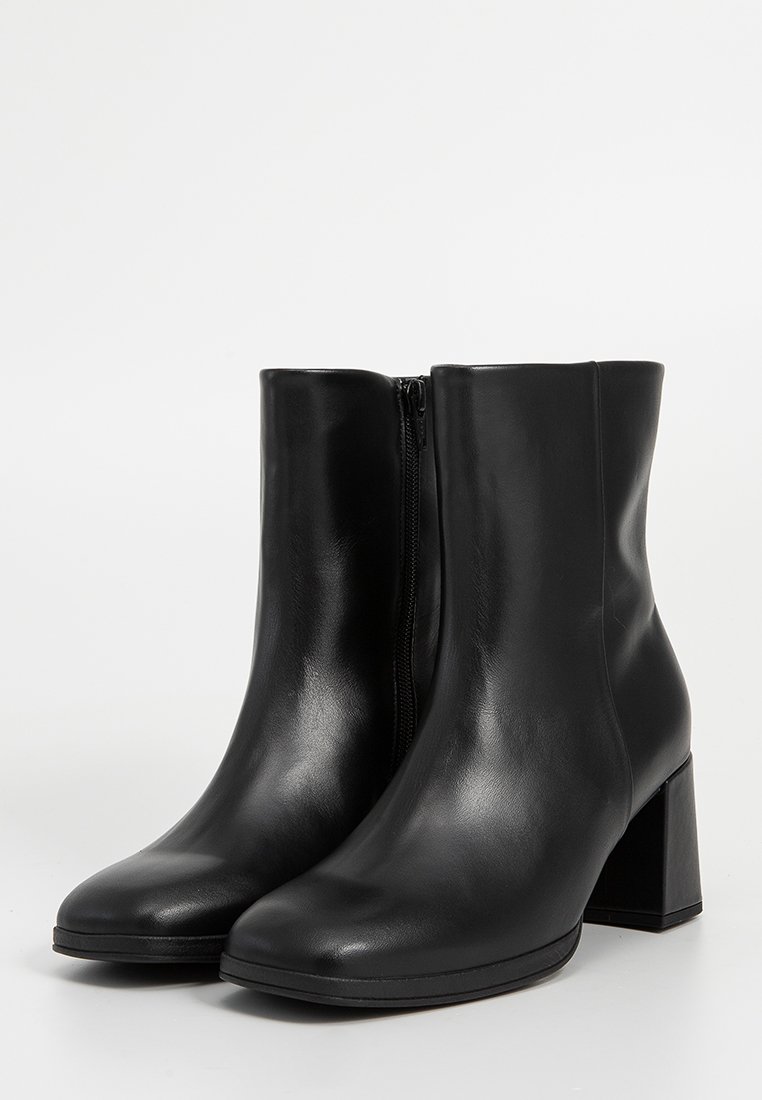 Fekete bokacsizmák sima bőrből, lekerekített orral, látható oldalsó cipzárral és vastag blokk sarkal.
