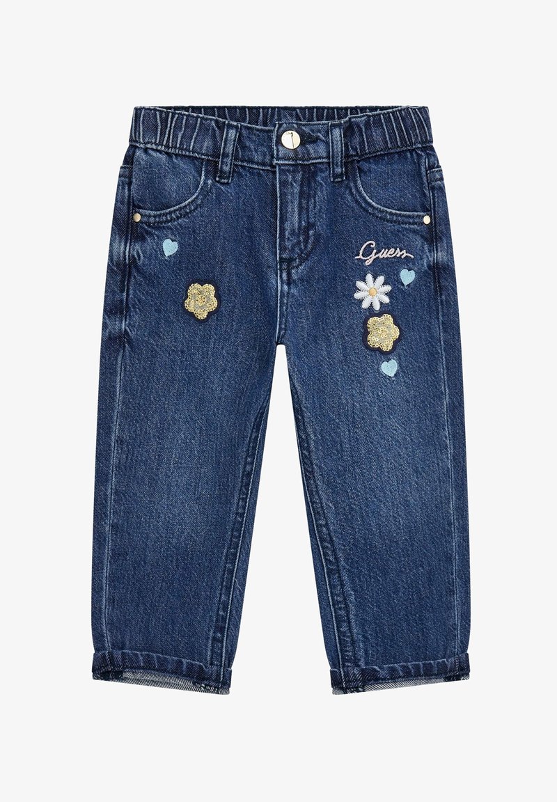 Jean en denim bleu foncé pour enfant avec des fleurs brodées, des cœurs bleus et le mot « Guess » sur le côté avant droit.