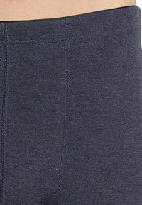 Dunkelblaue hochtaillierte Leggings aus dehnbarem Material mit vertikaler Rippstruktur und verstärkten Nähten für erhöhte Haltbarkeit.