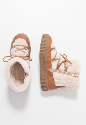 Paire de bottes d’hiver beige et crème doublées de fourrure, avec des lacets et des fermetures éclair latérales, une botte vue de dessus et une de côté.