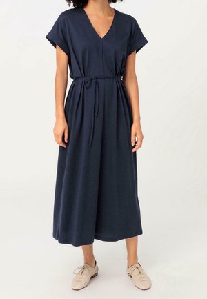 Marineblauwe jurk met korte mouwen, V-hals, verstelbare tailleband, vloeiende silhouet en zachte stoftextuur.