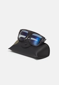 Ochelari de soare cu un cadru gros din plastic negru și lentile degradate albastre, așezați pe un toc texturat din piele neagră cu închidere prin buton.