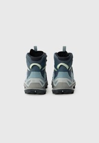 Hoge wandelschoenen in donkerblauw en licht teal, met een gestructureerde bovenkant, trekflap en robuuste zwarte zool met profielpatronen.