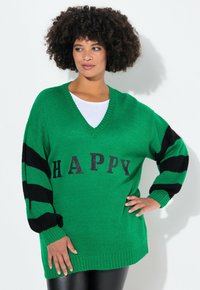 Maglione verde a maglia con scollo a V, caratterizzato da strisce nere sulle maniche e la parola "HAPPY" in glitter nero sulla parte anteriore.