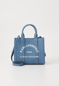Sac en denim avec double poignée supérieure et bandoulière amovible. Caractéristiques : logo en texte blanc et forme rectangulaire structurée.