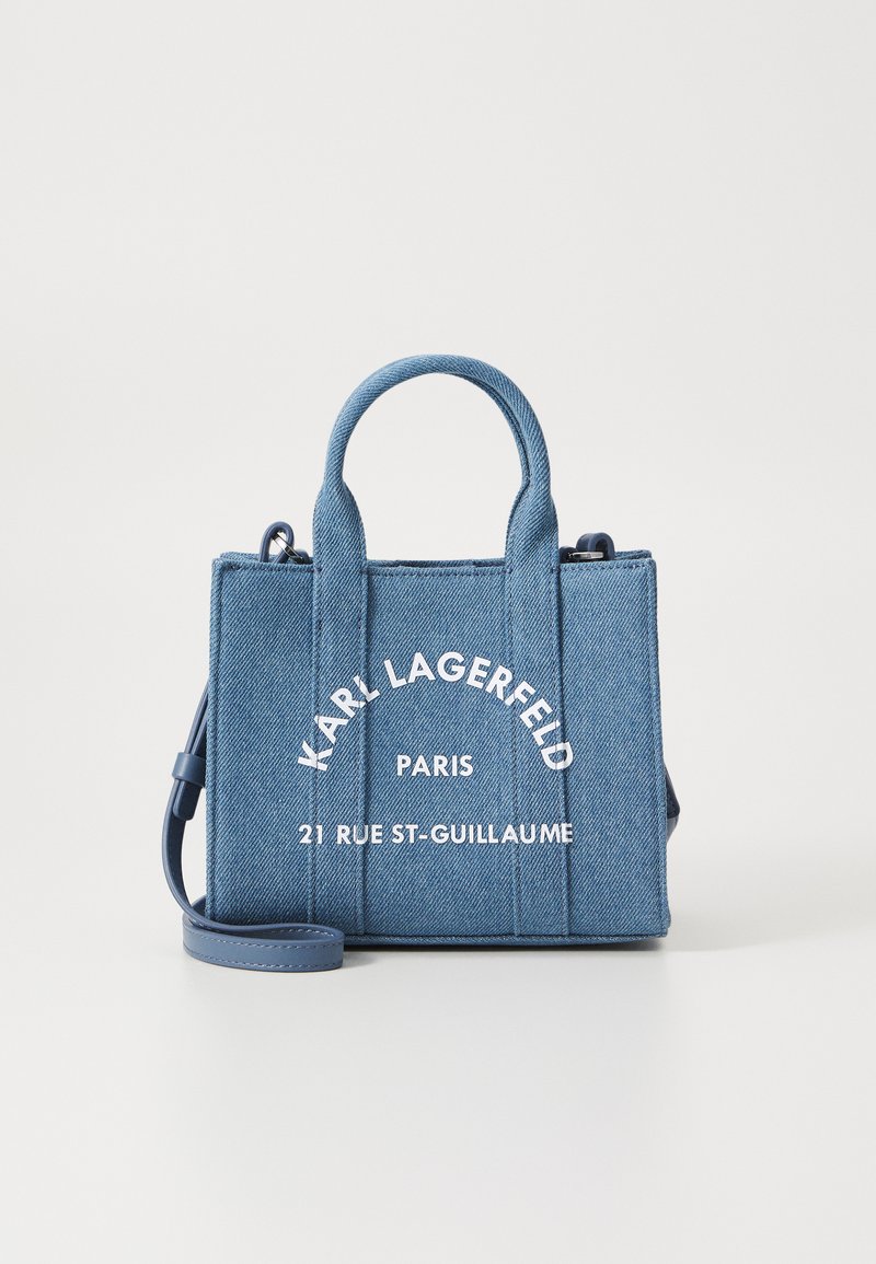 Sac en denim avec double poignée supérieure et bandoulière amovible. Caractéristiques : logo en texte blanc et forme rectangulaire structurée.