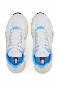 Sneaker bianco e grigio chiaro con tomaia in rete, dettagli blu, suola spessa e lacci bianchi. Logo visibile sulla linguetta e sulla soletta.
