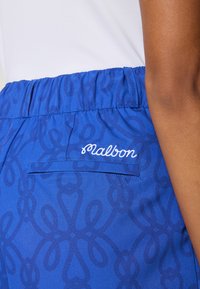 Modri šortsi z teksturiranim vzorcem, ki vsebuje zanke. Elastični pas in zadnji žep z vezenim logotipom „Malbon“. Mehak zaključek tkanine.