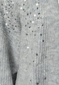 Grå stickad tröja med spridda silverpaljetter som visar en strukturerad tyg med ett mjukt och ombonat utseende.