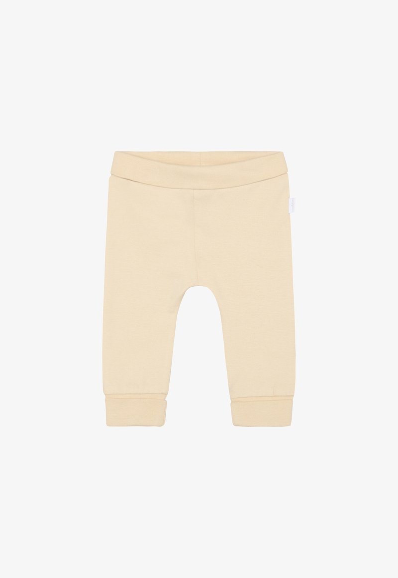 Leggings en coton beige clair avec une taille élastique, des chevilles effilées et une texture douce. Aucun motif ni ornement.