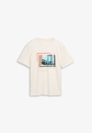 Krēmkrāsas T-krekls ar taisnstūrveida fotodruku, kurā attēlots ēkas logs un teksts par pilsētas ainavām un radošumu.