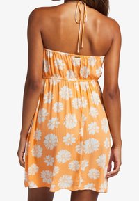Orange sommerkjole lavet af letvægtsstof, med hvide blomsterprint, smocket talje og bindebånd bagpå.