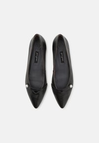 Bailarinas de cuero negro con punta afilada, que presentan un pequeño acento de perla en el lateral y un acabado suave y liso.