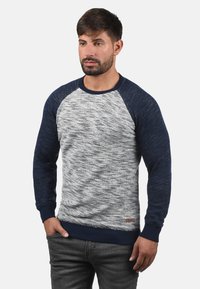 Herresweatshirt i grå og marineblå, med et teksturert strikkemønster, raglanermer og ribbestrikket halslinning og nedre kant. Lite logodetalj.