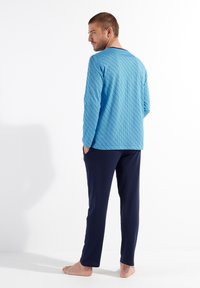 Blue long-sleeve top with geometric pattern, paired with navy pants. Soft fabric, relaxed fit, and pocket detailing on the trousers.