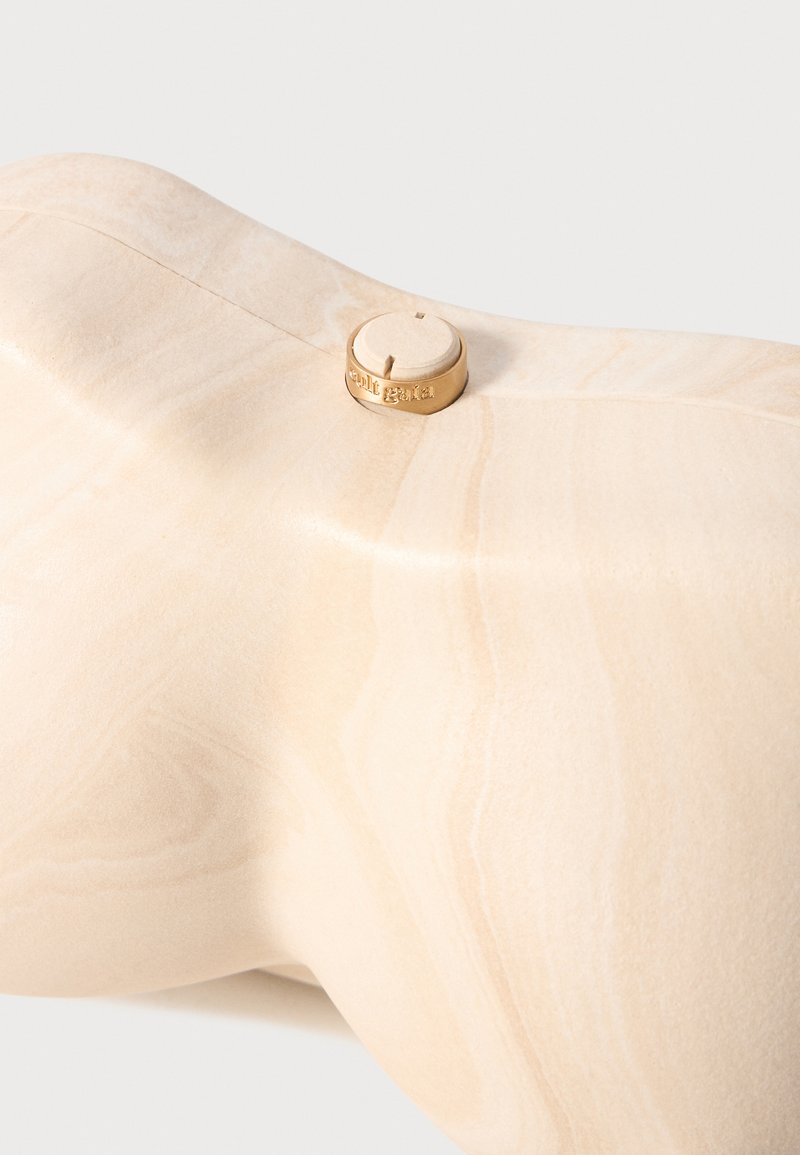 Light wood sculpture with smooth texture, featuring a small round gold accent. The surface has natural grain patterns and subtle tonal variations.