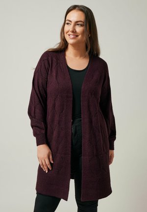 Cardigan lungo e aperto davanti in un profondo viola, con un motivo a diamante testurizzato e polsini a coste, indossato sopra una maglia nera.