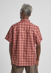 Kurzarm-Hemd aus karierter Baumwolle mit dunkelpink und hellpink Karo, ausgestattet mit einem Standardkragen und Rückenpasse.