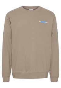 Beige sweatshirt with long sleeves, crew neck, and ribbed cuffs. Features a small, colorful "TOKYO" graphic on the left chest.