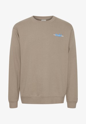 Bež kapuutsärk pika varrukaga, ümmarguse kaelusega ja soonikkoes mansettidega. Vasakul rinnal on väike, värviline "TOKYO" graafika.