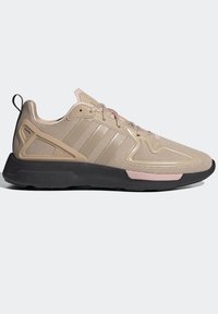 Beige athletic shoe with mesh upper, three horizontal stripes, pink accents, rubber sole, and a textured heel stabilizer.