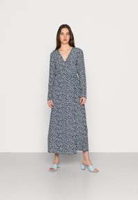 Vestido longo azul-marinho com padrão floral, decote em V e mangas compridas. Acompanhado por sandálias de salto bloco azul claro. Textura suave.