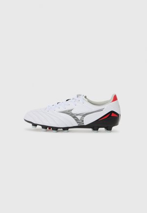 Crampons de football blancs avec des accents noirs et gris, tige texturée, six crampons noirs et des détails rouges sur le talon. Design à lacets.