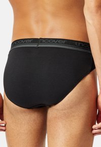 Caleçons en coton noir avec une ceinture élastique douce arborant le logo "uncover". Texture lisse et design ajusté, mettant en avant une vue arrière.