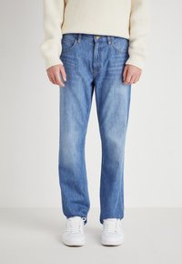 Lichtblauwe denim jeans met een relaxte pasvorm, voorzien van vijf zakken, een knoopsluiting en subtiele vervaging op de dijen. Draag ze met witte sneakers.