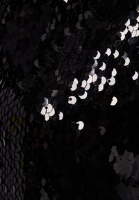 Tissu noir à sequins avec des sequins circulaires brillants de tailles variées. La texture est réfléchissante et lisse, créant un effet scintillant.