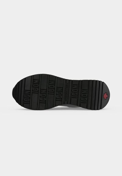 Semelle de chaussure en caoutchouc noir avec le mot "ICON" en relief répété et une petite feuille d’érable rouge près du talon.