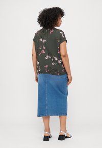 Floral blouse in dark green with short sleeves, paired with a light blue denim skirt. The blouse features pink and green flower patterns.