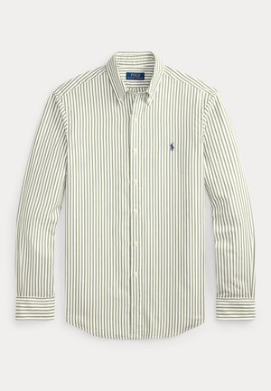 Πουκάμισο με ρίγες σε ανοιχτό πράσινο και λευκό. Διαθέτει κλασικό γιακά, μακριά μανίκια και μικρό ναυτικό λογότυπο στο στήθος.