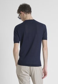 Suéter de punto de manga corta en color navy, hecho de material ligero, con cuello redondo y mangas ajustadas, que muestra una sutil textura en la tela.